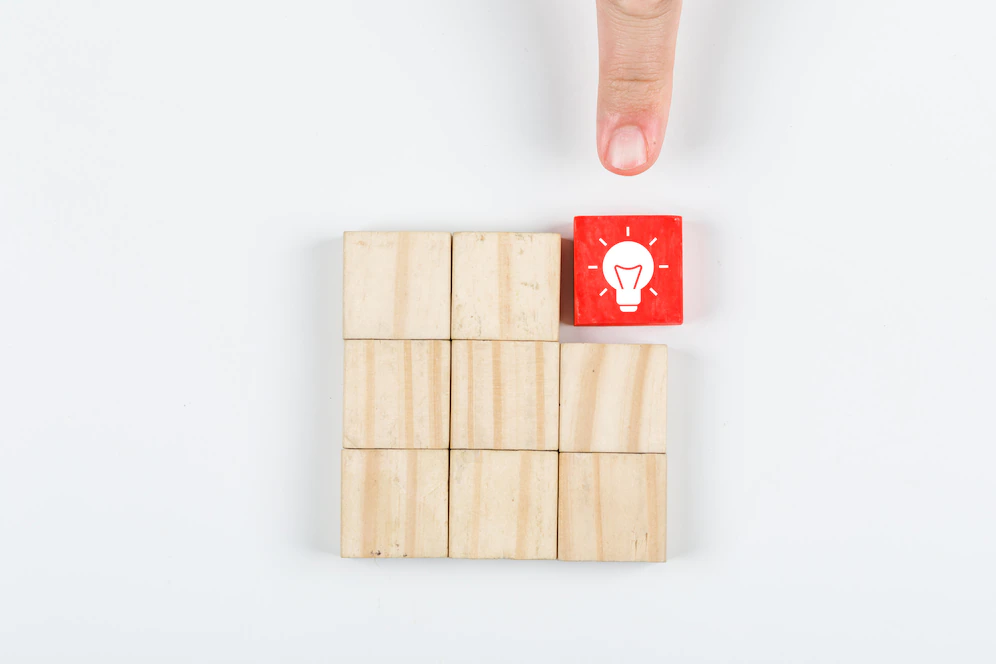 conceptual-idea-hand-pointing-idea-with-wooden-blocks-white-background-top-view-horizontal-image_176474-6771